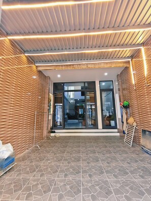 Una entrada moderna con un muro con diseño, una puerta de vidrio y piso de baldosas.