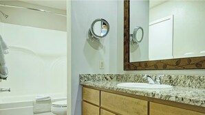 Un bagno con vasca, WC, mobile lavabo e specchio.