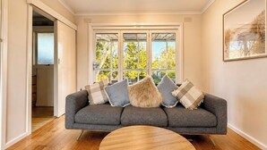 A modern living room with a grey sofa, a round coffee table, and a large window with a view of trees.