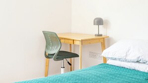 Ein Zimmer mit einem Bett, einem Schreibtisch, einem Stuhl und einer Lampe.