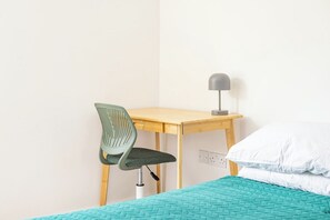 Ein Zimmer mit einem Bett, einem Schreibtisch, einem Stuhl und einer Lampe.