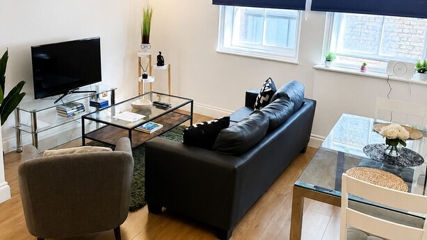 Een moderne woonkamer met een bank, fauteuil, salontafel en televisie.