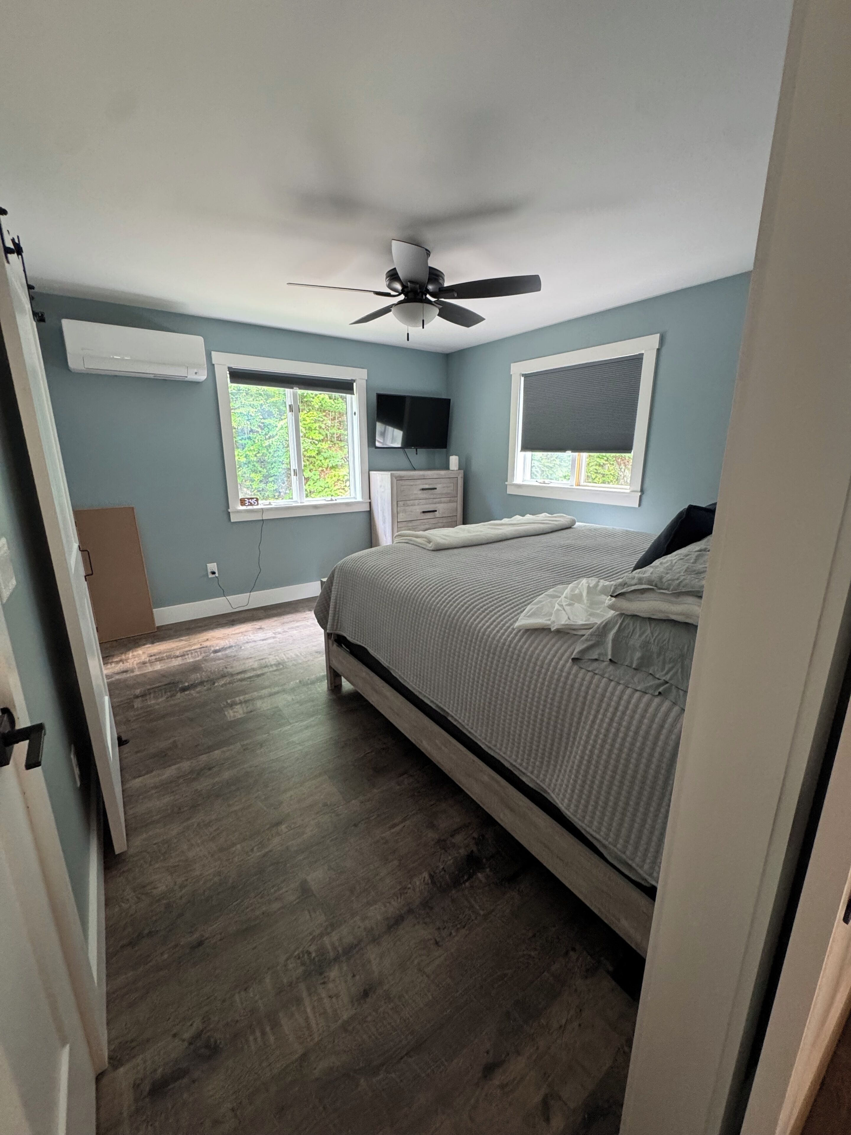 Une chambre à coucher avec un lit, un ventilateur de plafond, une commode et une fenêtre.