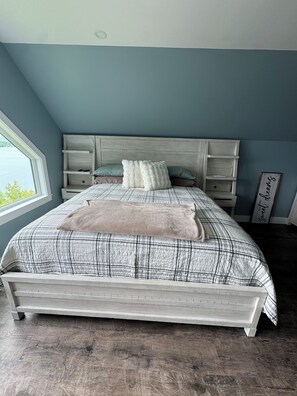 Een slaapkamer met een bed, een raam, een hoofdeinde en een nachtkastje.