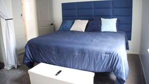A bedroom with a large bed, a white bedside table, and a door in the background. - 3BR Downtown Cleveland Home Near Stadiums Free Parking (Cleveland)