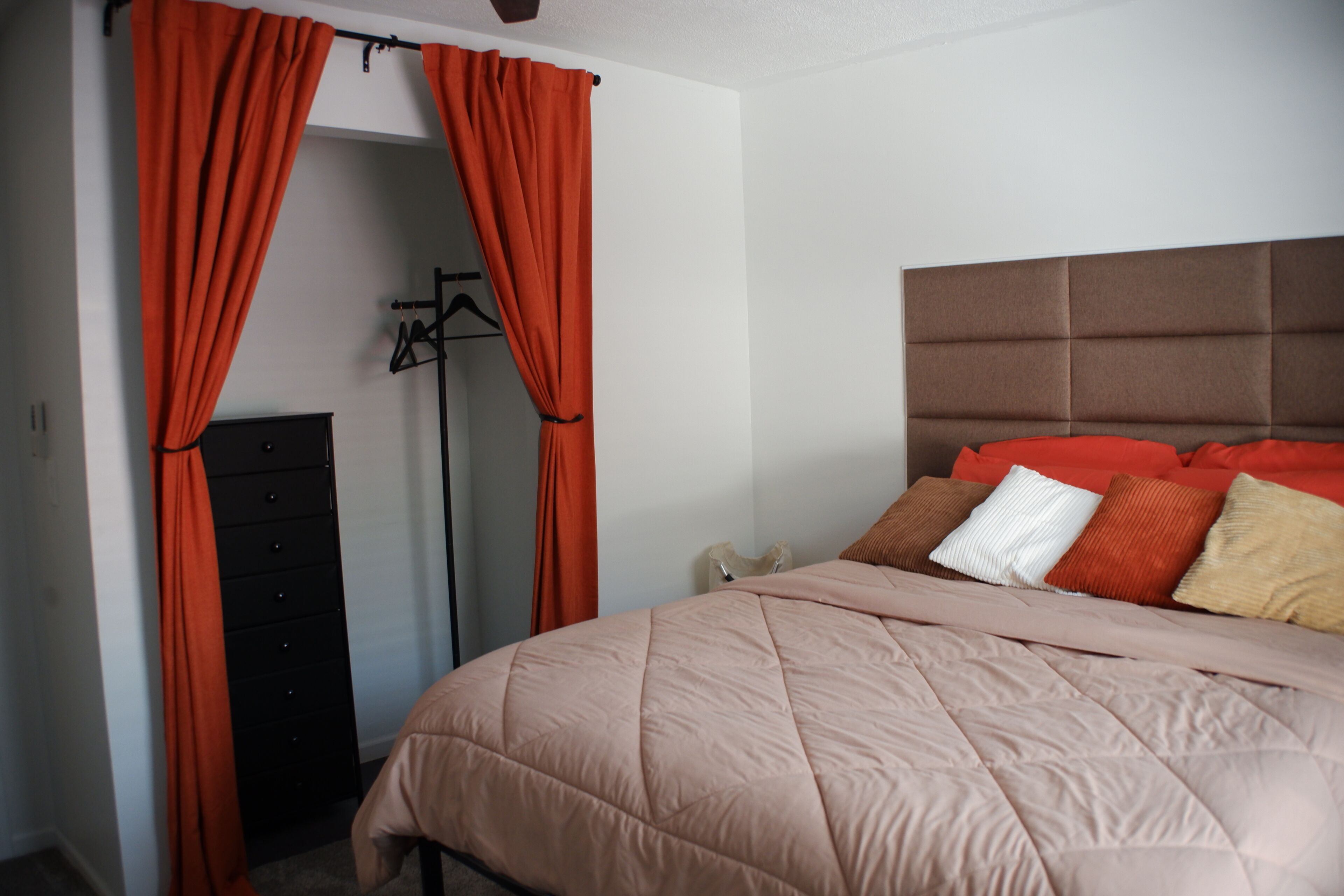 A bedroom with a bed, a wardrobe, and a hanging garment rack.