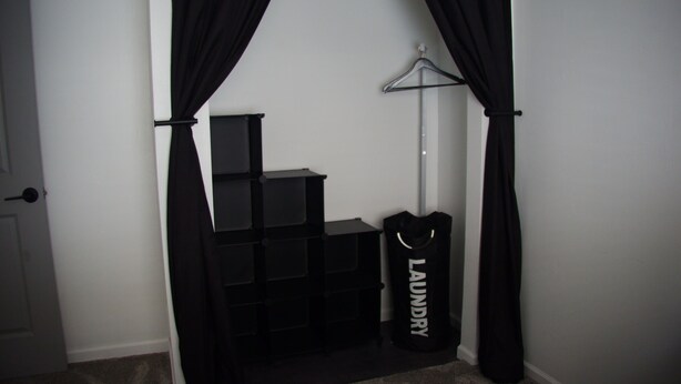 A room with a black wardrobe, a hanging rack, and a bag labeled 'LAUNDRY' against a white wall. - 3BR Downtown Cleveland Home Near Stadiums Free Parking (Cleveland)