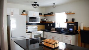 A modern kitchen with white cabinetry, a black countertop, and a built-in oven. - 3BR Downtown Cleveland Home Near Stadiums Free Parking (Cleveland)