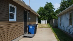 A residential area with two houses, a concrete pathway, and a blue trash bin. - 3BR Downtown Cleveland Home Near Stadiums Free Parking (Cleveland)