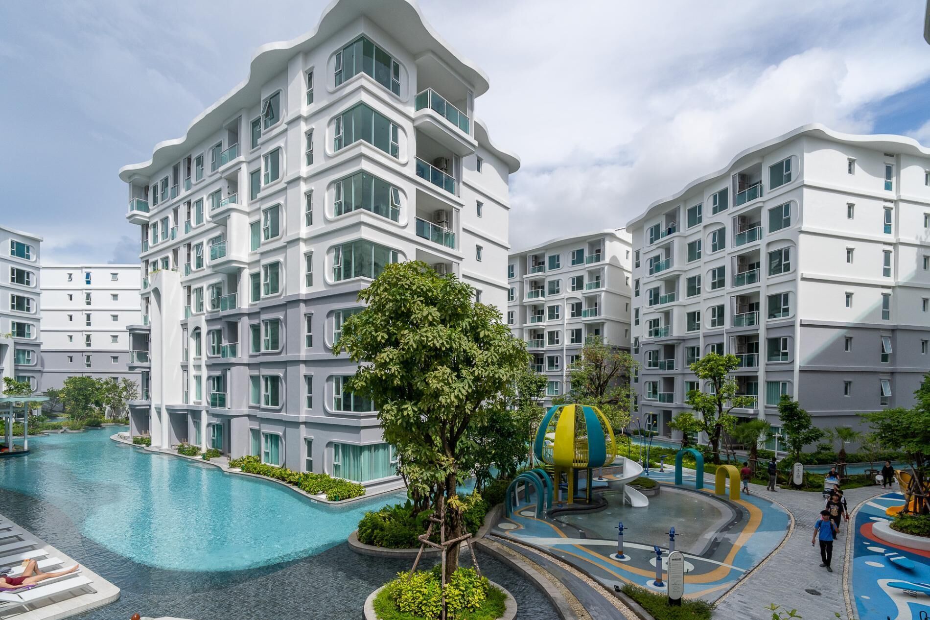 A modern residential building with a swimming pool and a children's play area.