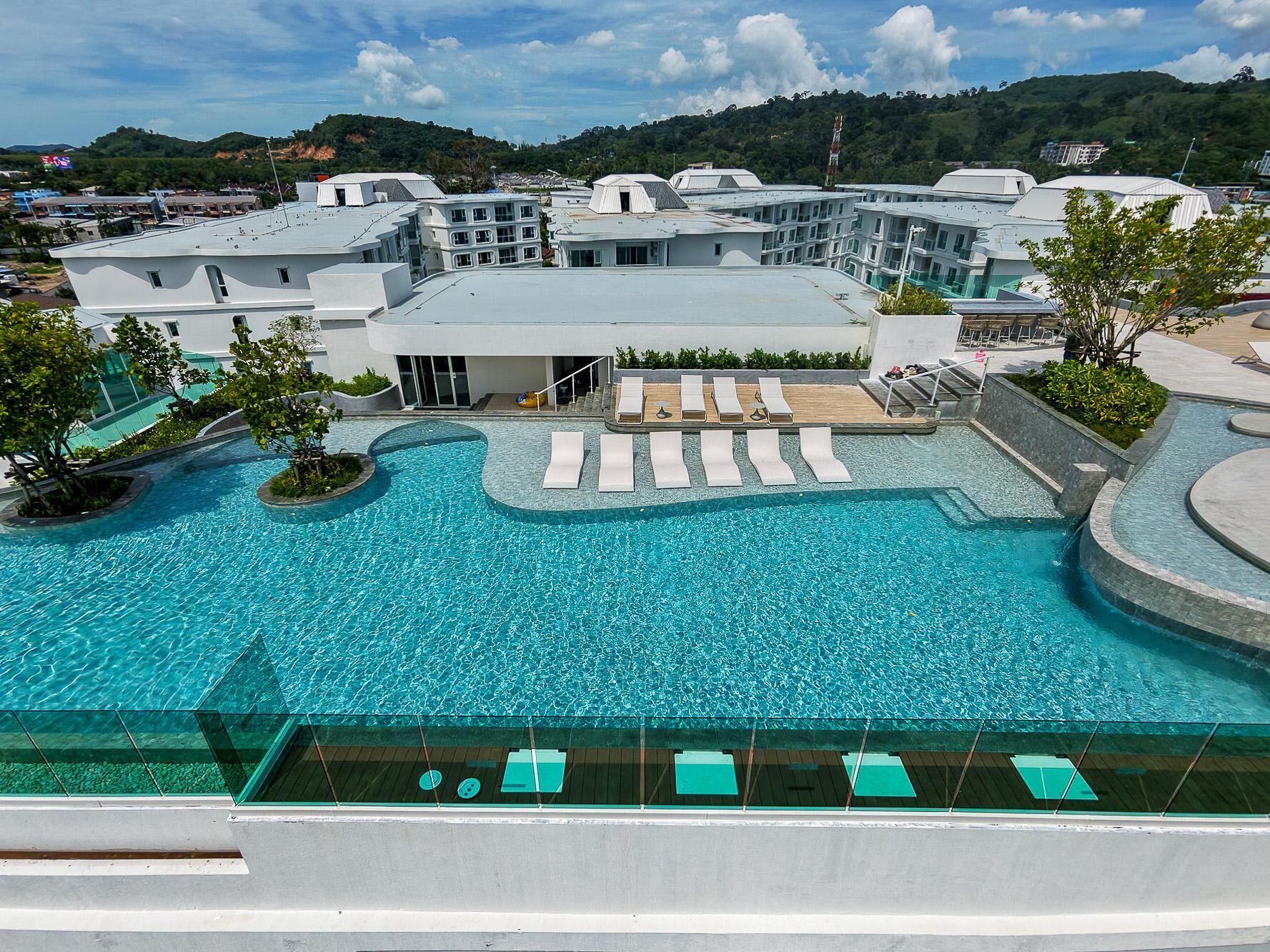 A large outdoor swimming pool with multiple lounge areas and a view of surrounding buildings.
