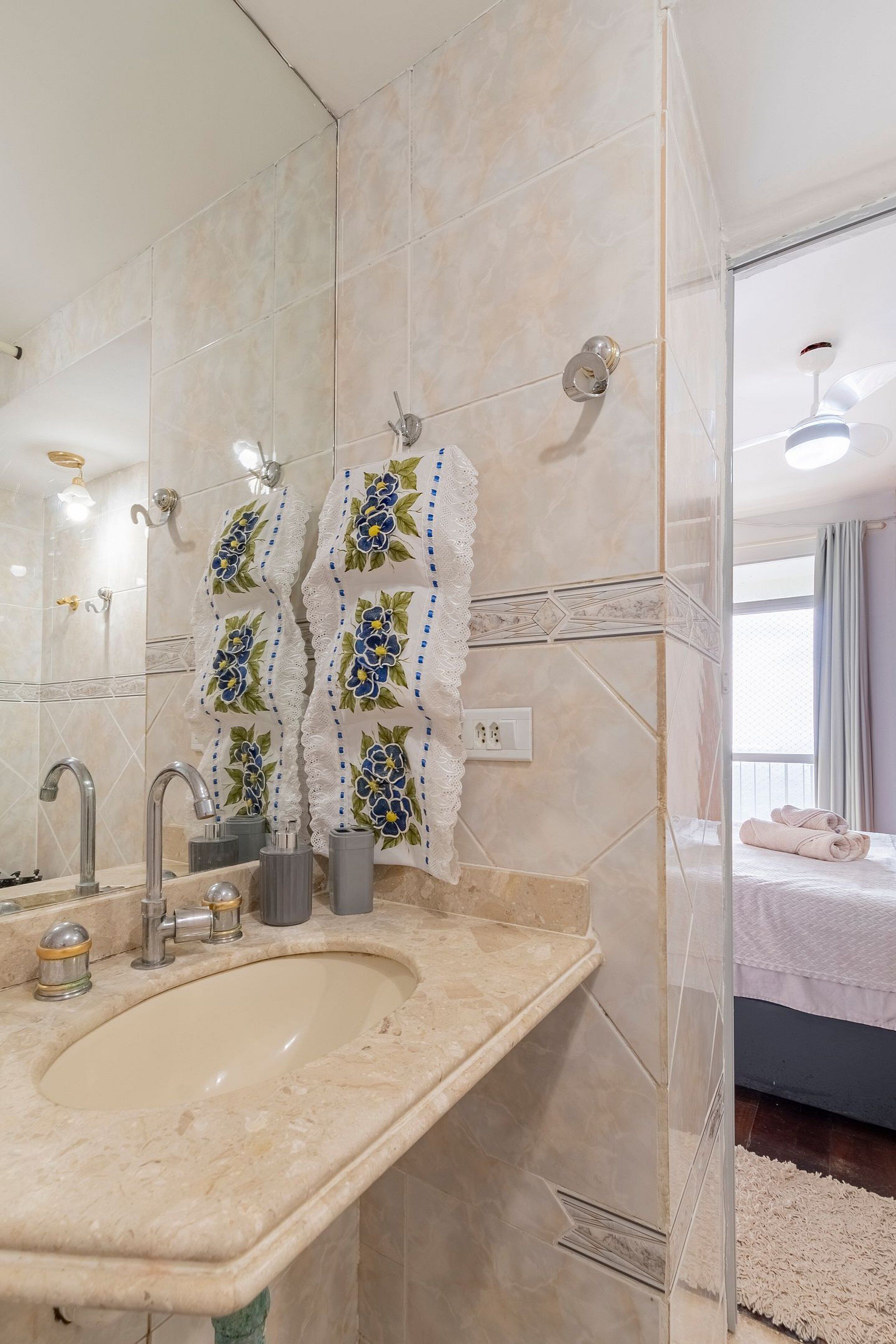 A bathroom with a large mirror, a sink with modern faucets, and a shower area.