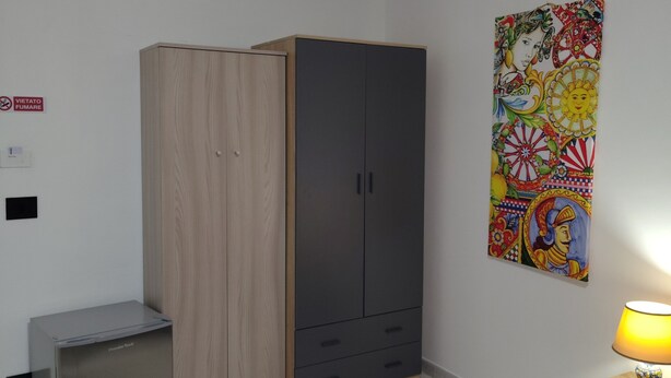 A bedroom with a wardrobe, a desk, a chair, a bed, and a wall-mounted lamp. - Guest House Tondo Vecchio Caltagirone (Caltagirone)