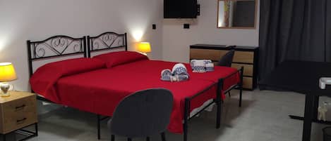 A hotel room with a bed, bedside table, lamp, desk, chair, TV, and a mirror.