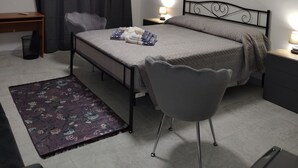 A small, well-lit bedroom with a single bed, a chair, a desk, and a nightstand. - Guest House Tondo Vecchio Caltagirone (Caltagirone)
