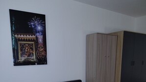 A room with a dark-colored sofa, a wardrobe, and a wall-mounted picture. - Guest House Tondo Vecchio Caltagirone (Caltagirone)