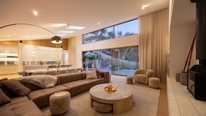 A modern living room with a sofa, coffee table, and chairs. There is a kitchen in the background with a dining area. - Ms Dana Bridgewater with heated magnesium pool (Blairgowrie)