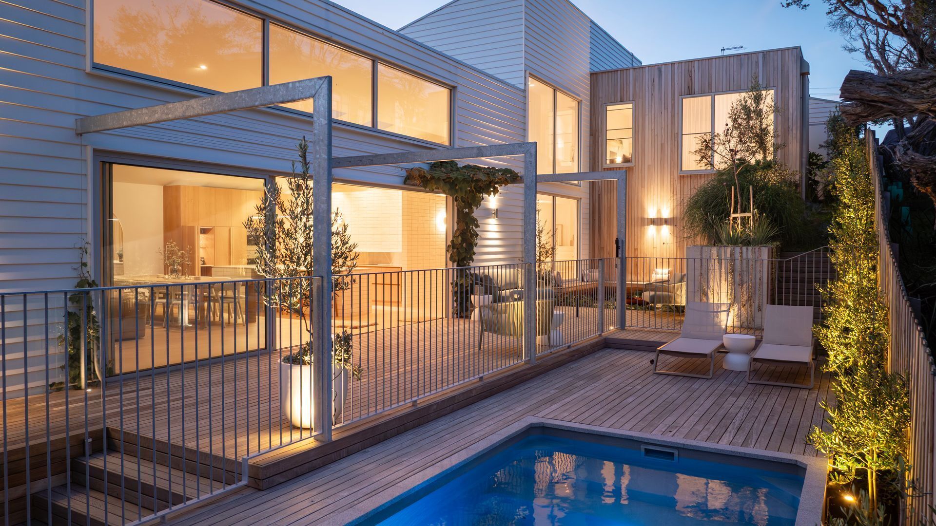 A modern house with a swimming pool, outdoor seating, and large windows.