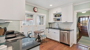 Una cocina con armarios blancos, un lavavajillas de acero inoxidable y una mesa de madera.