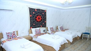 A hotel room with three single beds, a large tapestry, and a patterned floor. - Samarkand City Center Hotel (Samarkand)