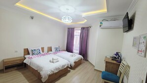 A hotel room with two beds, a desk, a chair, and an air conditioning unit. - Samarkand City Center Hotel (Samarkand)