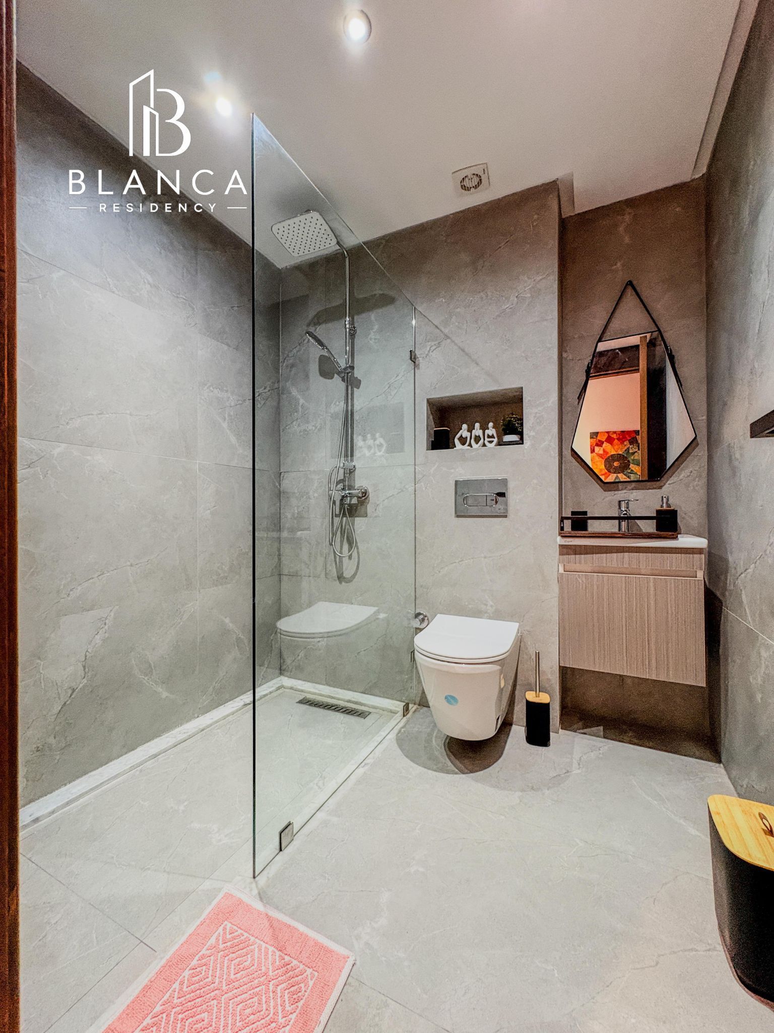 Une salle de bain moderne avec une douche à parois de verre, des toilettes et un lavabo avec un miroir au-dessus.