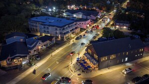 An aerial view of a town with a mix of residential and commercial buildings, a main road with traffic, and a restaurant with outdoor seating.