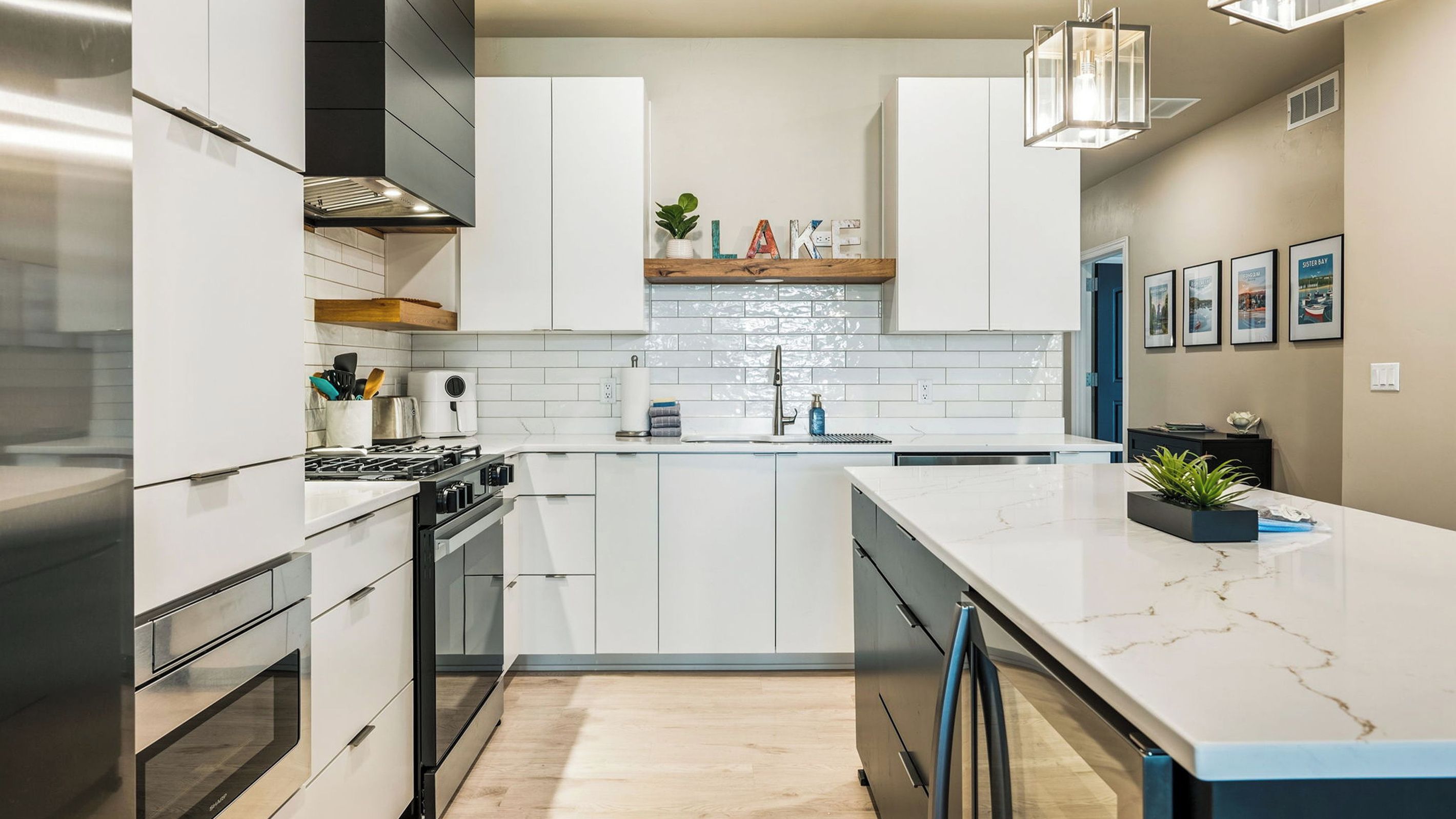 A modern kitchen with white cabinetry, a marble countertop, and a built-in oven.