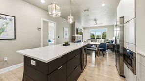 A modern kitchen with a large island, dark cabinetry, stainless steel appliances, and a view to the outdoors.