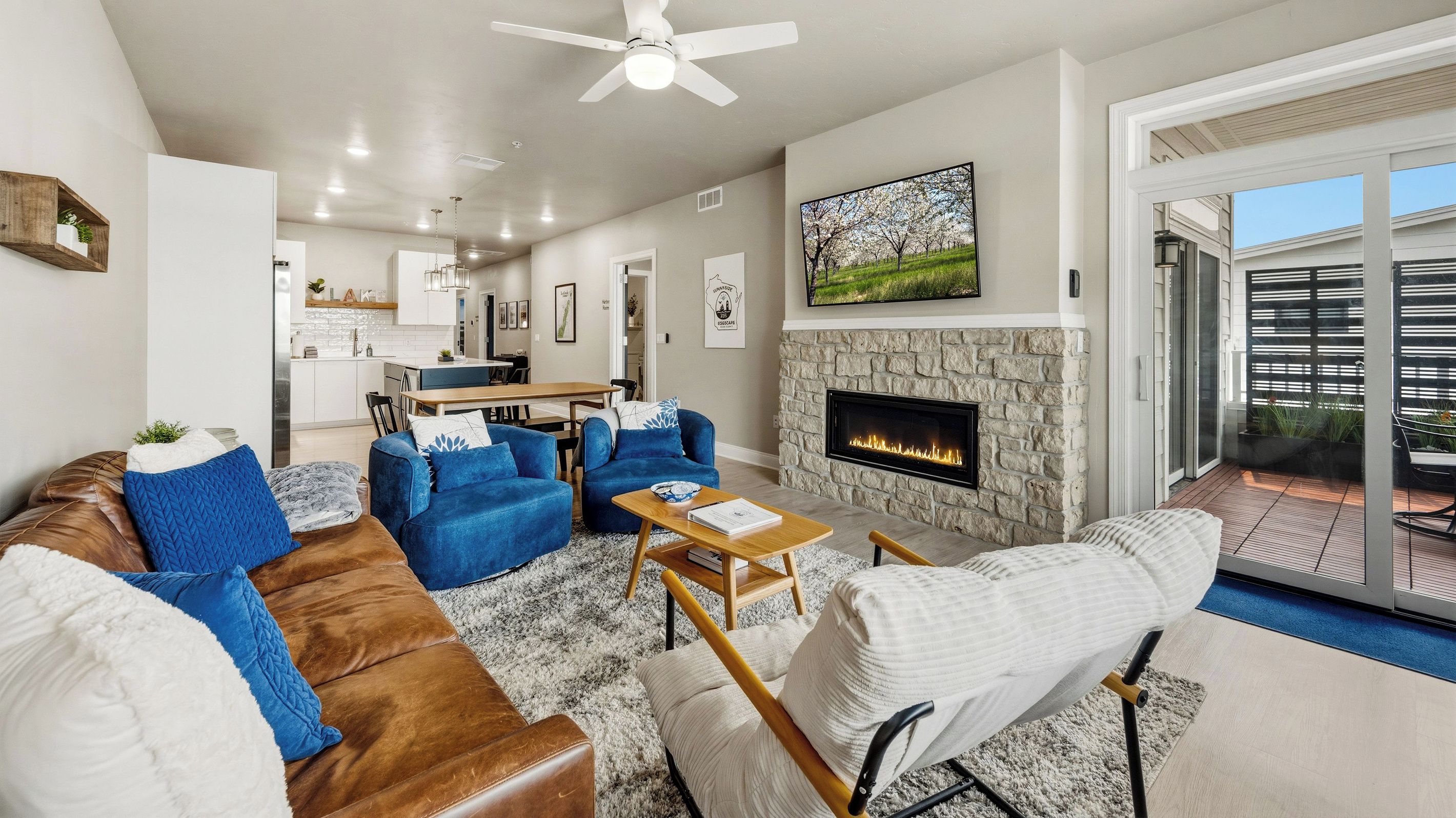A modern living room with a fireplace, a dining area, and a view of the outdoors.