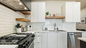 A modern kitchen with white cabinetry, a stainless steel range, and a built-in dishwasher.