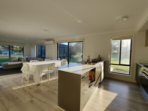 Una cocina moderna con una isla central, ventanas amplias y una zona de comedor con sofá y mesa.