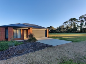 A modern two-story house with a garage, surrounded by a well-maintained lawn and trees.