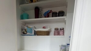 Une cuisine avec des étagères blanches où sont rangés divers ustensiles de cuisine, un grille-pain et une bouilloire.