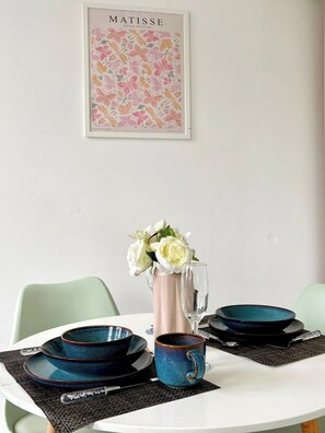 Una mesa de comedor con un jarrón de flores, platos y una copa.