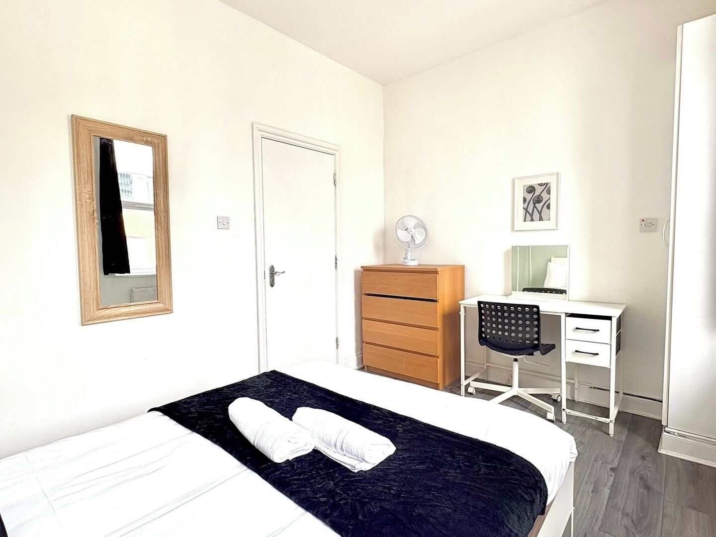 A bedroom with a bed, a dresser, a desk, and a chair.
