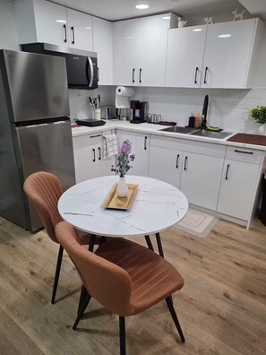 A modern kitchen with white cabinets, stainless steel appliances, and a round table with a vase.