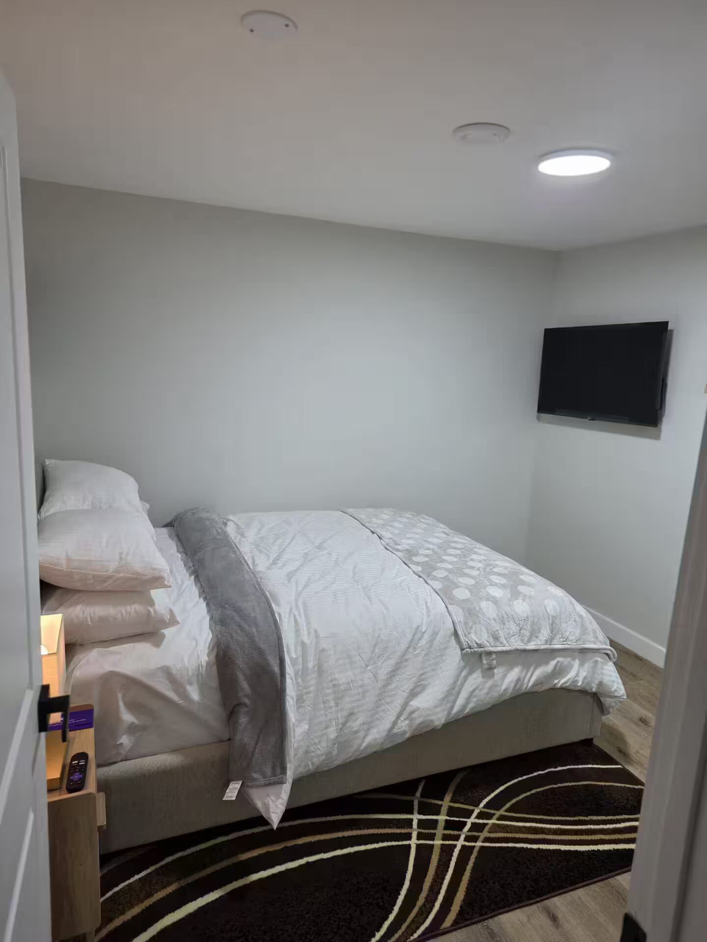 Ein Schlafzimmer mit Bett, Nachttisch und einem Wand-Fernseher.