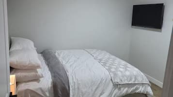 Ein Schlafzimmer mit Bett, Nachttisch und einem Wand-Fernseher.