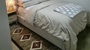 Una camera da letto con un letto, un comodino, una lampada e un tappeto decorato.