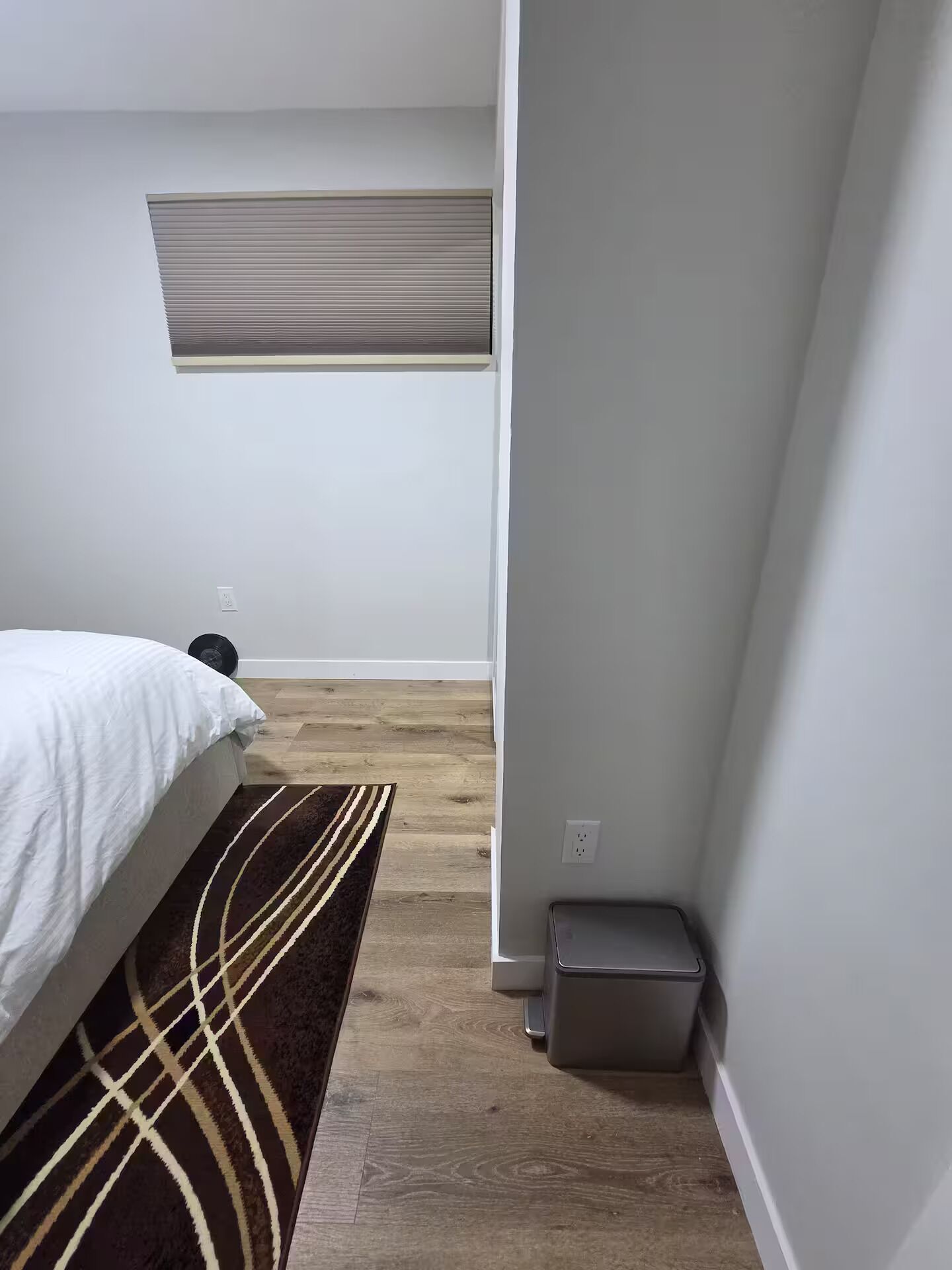 Ein Schlafzimmer mit Bett, Teppich, Heizkörper und Mülleimer.