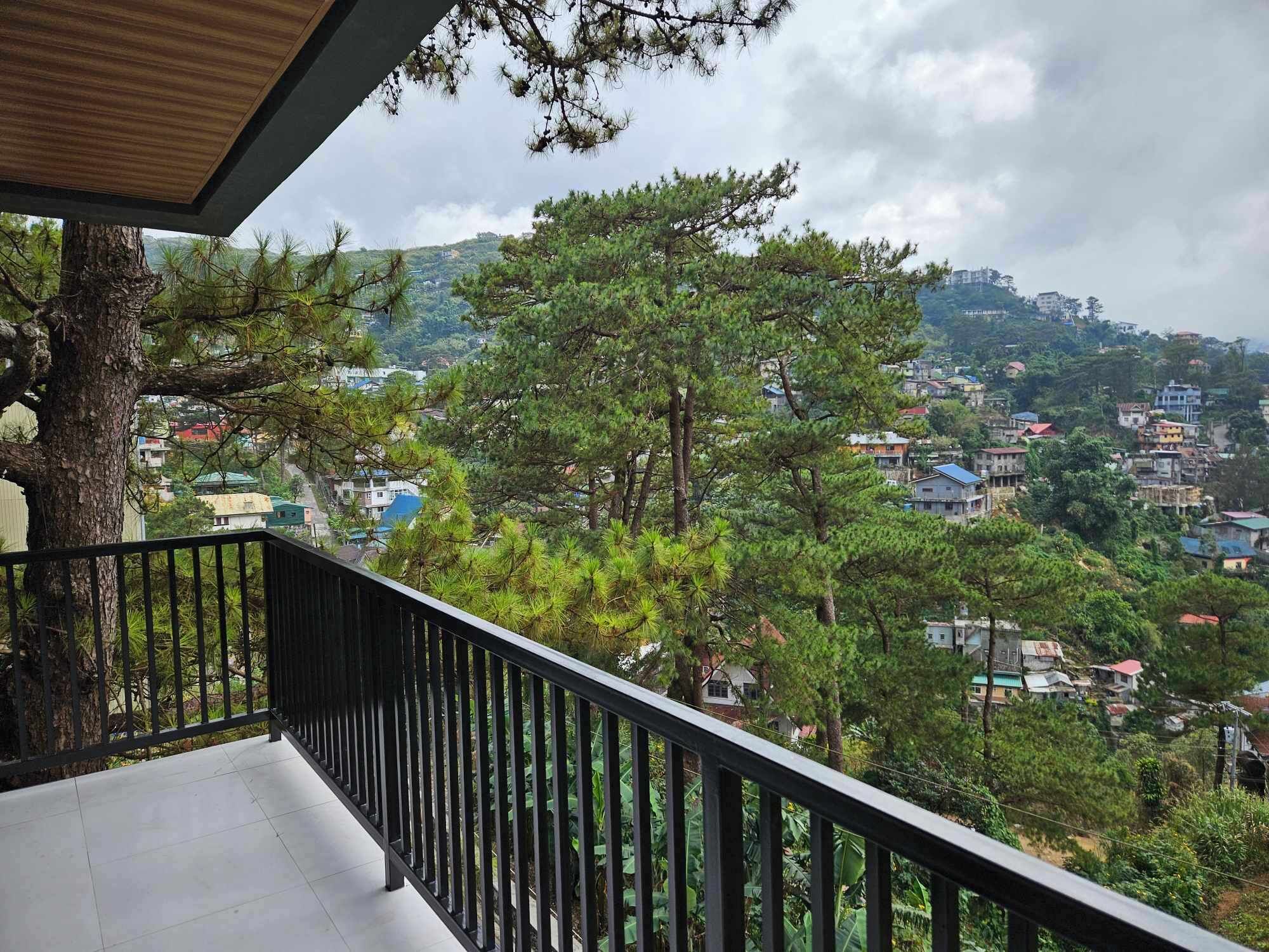 A balcony with a view of a residential area and trees.