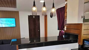 Una cucina moderna con un piano di lavoro nero, pannelli a parete in legno e lampade a sospensione.