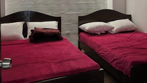 Una stanza con due letti, ognuno con una testiera scura e una coperta rossa. Le pareti presentano una texture decorativa.
