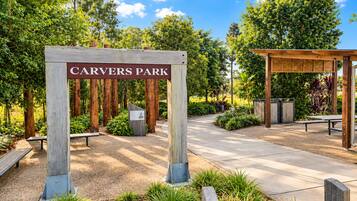 A park entrance with a sign reading 'CARVERS PARK' surrounded by trees and a wooden pergola.