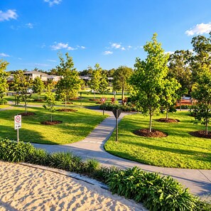 Zona residencial ajardinada con acera, árboles y señal de zona compartida.