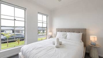A hotel room with a large bed, two bedside lamps, and a view of a parking area through the windows.
