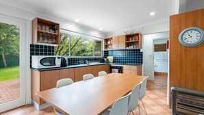 Une cuisine moderne avec un coin repas, comprenant un four à micro-ondes encastré, une grande fenêtre et une horloge murale.