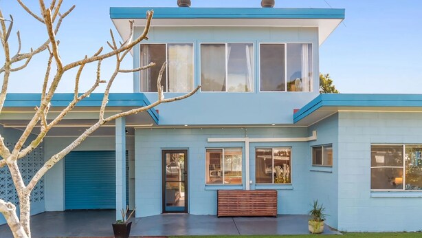 Une maison moderne à deux étages, dotée d’un garage, de grandes fenêtres et d’un petit jardin à l’avant.