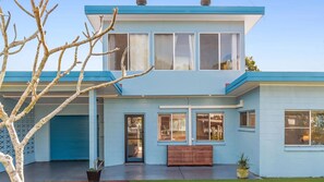 Una casa moderna de dos pisos con garaje, ventanas amplias y un pequeño jardín delantero.